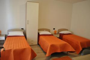 two beds in a room with orange sheets at Raxul Room in Sestu