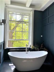 a white bath tub sitting next to a window at Eco Hotel Plantage Rococo in Velsen-Zuid