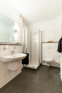 a white bathroom with a sink and a toilet at Schäfers Hotel in Cloppenburg