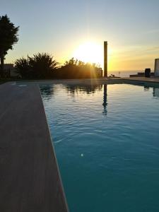 a swimming pool with the sunset in the background at B&B Villa Di Giorgi in Cefalù