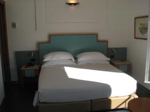 Hotel Belvedere في بورتوفينيري: غرفة نوم بسرير ذو شراشف ووسائد بيضاء