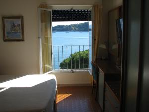 Schlafzimmer mit einem Bett und Blick auf das Wasser in der Unterkunft Hotel Belvedere in Porto Venere
