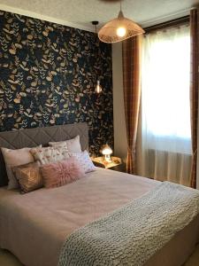 - une chambre avec un grand lit et un mur fleuri dans l'établissement Gîte de la Coussotterie Sud Vendée 4 **** 8 pers, à Sainte-Gemme-la-Plaine