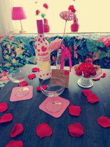 - une table avec une bouteille de vin et des coeurs en papier rouge dans l'établissement Hotel B&B LeLa, à Fauquemont