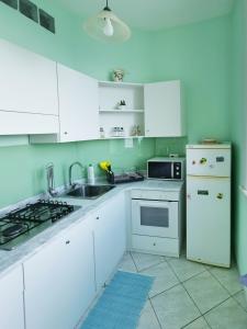 La cuisine blanche est équipée d'un évier et d'un réfrigérateur. dans l'établissement Casa Consy, à Sorrente