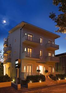 - un grand bâtiment blanc avec des lumières devant dans l'établissement Residence Caterina, à Cattolica
