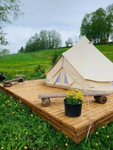 una tenda su una terrazza di legno con una pentola di fiori di Murimäe Winery glamping a Otepää