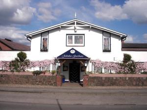 a white building with a blue awning in front of it at Pension Jahnkes Gasthaus in Todesfelde