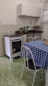 a kitchen with a table and a stove top oven at Chalé saí azul in Penedo