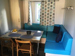 uma sala de estar com um sofá azul e uma mesa em Mobil Home pour 6 personnes climatisé à quelques minutes des plages em Agde