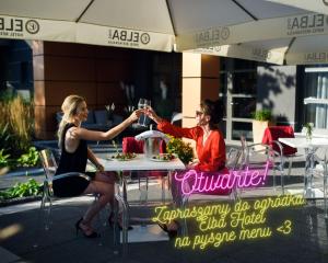 dwie kobiety siedzące przy stole pijące wino w obiekcie Elba Hotel w mieście Ostrołęka