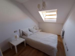 Dormitorio blanco con cama y tragaluz en Costa da Morte "Paraiso de Galicia", en Ponteceso