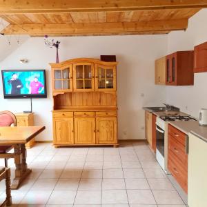 a kitchen with wooden cabinets and a tv on the wall at U Ingi in Szypliszki