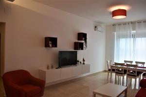 ein Wohnzimmer mit einem TV und einem Esszimmer in der Unterkunft Melograno Home in Neapel
