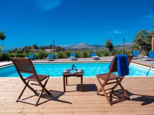 アファンドウにあるZizi Sea View Villaのスイミングプールの横に椅子2脚とテーブル1台