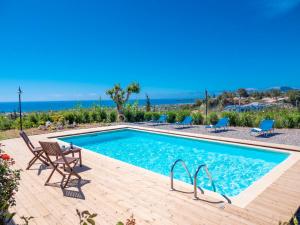 einen Pool mit Stühlen und das Meer im Hintergrund in der Unterkunft Zizi Sea View Villa in Afandou