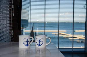 two coffee mugs sitting on a table in front of a window at nauticaluxapartamenty.pl in Giżycko