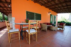 un patio con mesa, sillas y una pared de color naranja en Villa Tara Gaeta, en Gaeta