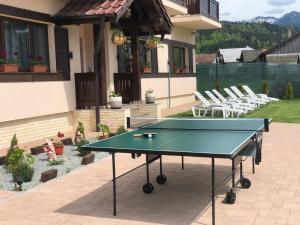 a ping pong table on a patio with chairs at Pensiunea Maria in Colibiţa