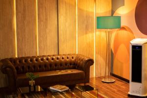 a living room with a leather couch and a lamp at Jockey Class Hotel in Teresina