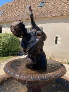 a statue of a boy playing in a fountain at La Ferme Buissonnière in Bardou