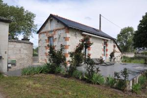 uma casa de pedra com um jardim em frente em PETITE MAISON des ROSES - GITE 2 Personnes em Brain-sur-Allonnes