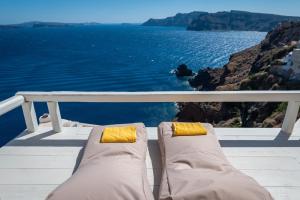 a pair of chairs sitting on a balcony looking at the ocean at Armeni Luxury Villas in Oia