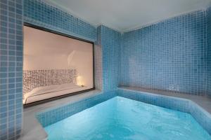 a blue tiled bathroom with a large mirror and a tub at Armeni Luxury Villas in Oia