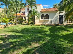 a house with a yard with palm trees at Casa del Arte, a luxury beachfront villa with private pool in Tela