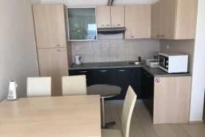 eine Küche mit einem Tisch, Stühlen und einer Mikrowelle in der Unterkunft Apartment Jadranka Selce No 64 in Selce