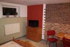 a living room with a tv on a wooden dresser and a table at Ferienwohnung Friedrichshagen in Berlin