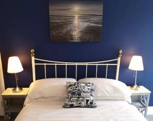 a bedroom with a bed with a blue wall and two lamps at The Sunfold in Weston-super-Mare