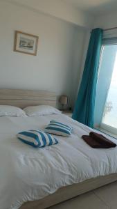 a white bed with blue pillows and a window at Flat 2 Blue Waves in St Paul's Bay