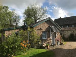 una pequeña casa de ladrillo con un jardín delante de ella en Maison Marguerite, en Lemiers