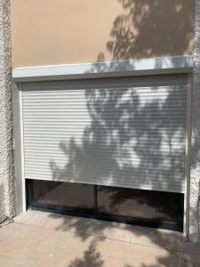 a garage door with a shadow on the side of a building at Joli studio tout confort avec toutes commodités in Vaulx-en-Velin