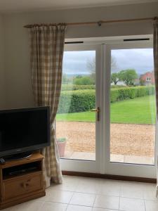 a living room with a television and a sliding glass door at Wisteria Cottages are self catering cottages in a beautiful village location in Dorrington