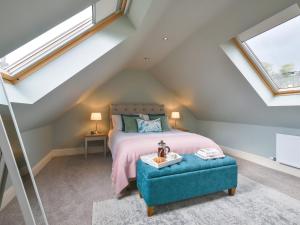 - une chambre mansardée avec un lit et une ottomane bleue dans l'établissement Walton House Cottage, à Chapel-en-le-Frith