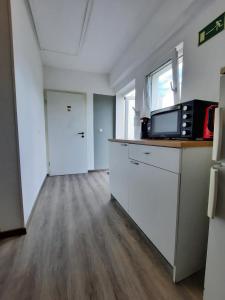 eine Küche mit weißen Schränken und einer Mikrowelle in der Unterkunft Pension Bei Valentina in Wertheim