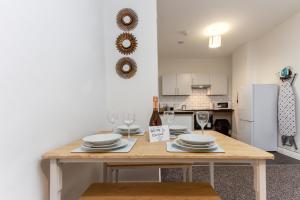 a kitchen with a table with plates and wine glasses at Kings Court Modern Aparthotel, Town Centre - Blackpool Resort Collection in Blackpool