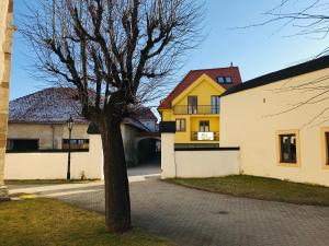 a tree in front of a yellow and white building at Apartmán Kežmarok in Kežmarok