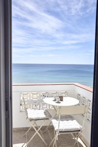 uma mesa e cadeiras numa varanda com o oceano em Casas Sul no Burgau