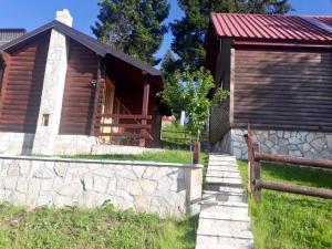 une cabane en rondins avec un mur en pierre à côté d'un bâtiment dans l'établissement Cozy Cabin, à Žabljak