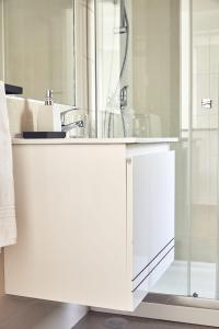 een witte badkamer met een wastafel en een douche bij Casas Sul in Burgau