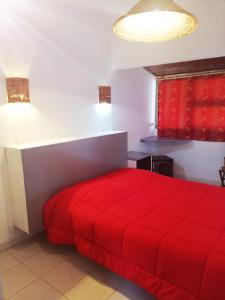 un letto rosso in una camera bianca con coperta rossa di Valinco Village a Porto Pollo