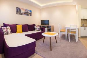 ein Wohnzimmer mit einem lila Sofa und einem Tisch in der Unterkunft Branka Apartments in Tivat