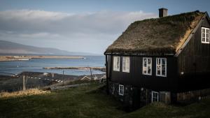 a house with a grass roof on a hill next to the water at Traditional Faroese house in Tórshavns city center in Tórshavn