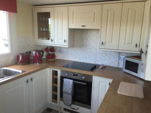 uma cozinha com armários brancos e um forno com placa de fogão em Erradill Cottage em Southend