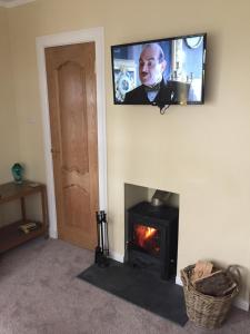 a living room with a fireplace and a tv on the wall at Erradill Cottage in Southend