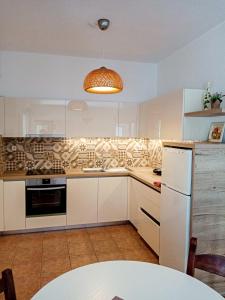 a kitchen with white cabinets and a white refrigerator at Sirines Apartments in Palekastron