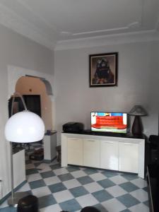 a living room with a television and a checkered floor at Appartement Maroc Safi in Safi